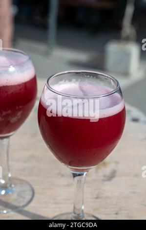 Famosa birra rossa lambic kriek, birra alla ciliegia fresca servita all'aperto nel festival belga della birra a Durbuy, speciale bicchiere di birra belga alle luci del sole, vicino a u Foto Stock