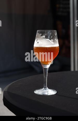 Famosa birra rossa lambic kriek, birra alla ciliegia fresca servita all'aperto nel festival belga della birra a Durbuy, speciale bicchiere di birra belga alle luci del sole, vicino a u Foto Stock