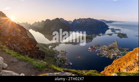 Il sole di mezzanotte si innalza all'orizzonte, immergendosi nel suggestivo paesaggio di Reinebringen, nelle isole Lofoten, in una luce soffusa, evidenziando la tranquillità del re Foto Stock