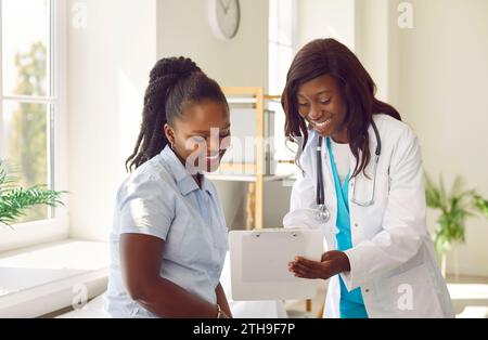Paziente donna che cerca di riportare il fascicolo con appuntamento seduto sul divano in clinica con un medico. Foto Stock