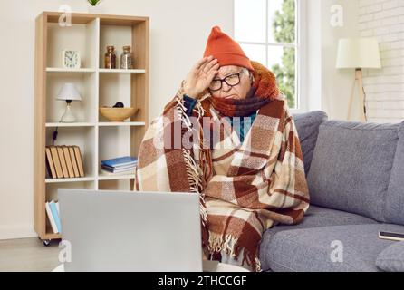 Anziano malato seduto sul divano a casa e con videochiamata online a casa. Foto Stock
