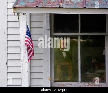 Un ritratto di Abraham Lincoln è appeso all'interno e alla vecchia fattoria del Vermont con una bandiera americana appesa al muro esterno Foto Stock