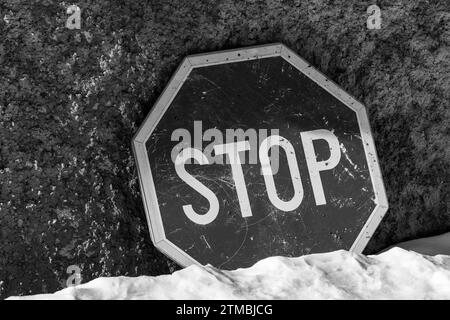 Fermata , segnaletica stradale su sfondo cemento. Terreno coperto di neve.colori bianco e nero. Informazioni. Monocromatico. Foto Stock