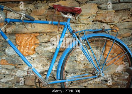 Fascino rustico: Bicicletta antica sospesa su sfondo di pietra Foto Stock