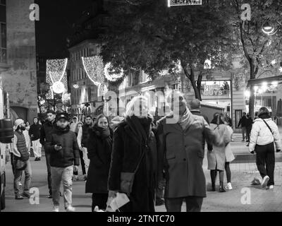 Un'accattivante fotografia in bianco e nero che cattura individui concentrati e sfocati nell'incantevole mercatino di Natale di Strasburgo Foto Stock