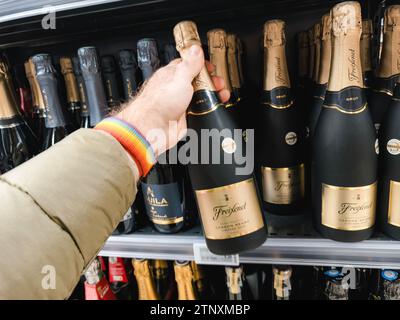 Parigi, Francia - 10 novembre 2023: Un punto di vista POV cattura un cliente che raggiunge una bottiglia di champagne Freixenet dagli scaffali, preparandosi per un up Foto Stock