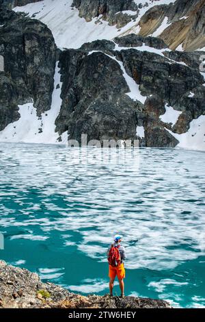 Un solitario escursionista contempla la vastità del fascino ghiacciato del lago Wedgemount. Foto Stock