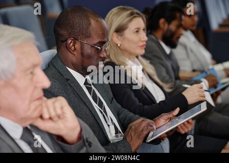 Gruppo di persone d'affari sedute di fila e che prendono appunti durante una conferenza d'affari Foto Stock