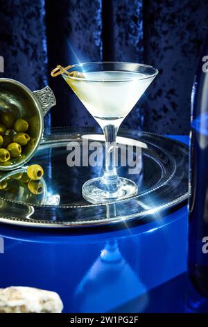 Foto ravvicinata del cocktail margarita con olive in piatto su vassoio d'argento d'epoca sul banco blu del bar del ristorante di lusso. Foto Stock