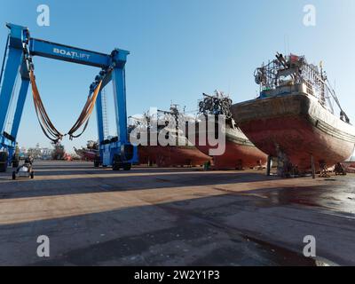 Gru e grandi navi in un bacino di carenaggio probabilmente per manutenzione a Essaouira, la "città ventosa", Marocco. 21 dicembre 2023 Foto Stock