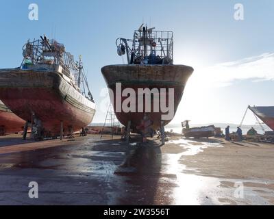 Grandi navi e lavoratori in un bacino di carenaggio probabilmente per manutenzione a Essaouira, la "città ventosa", in Marocco. 21 dicembre 2023 Foto Stock