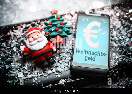 FOTOMONTAGE, smartphone mit Aufschrift Weihnachtsgeld, Weihnachtsmannfigur und Tannenbaum auf Computertastatur Foto Stock