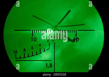 Elicottero militare alla vista ottica di un fucile da cecchino. Luce verde del dispositivo di visione notturna. Il concetto di operazioni militari, internazionali Foto Stock