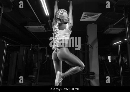 L'attraente ragazza procace si tira al bar. Concetto di fitness e bodybuilding. Supporti misti Foto Stock