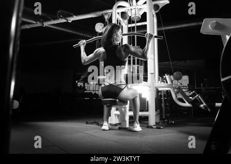 Una deliziosa sportiva esegue l'esercizio. Trazione dell'asse. Esercizio per i muscoli della schiena. Il concetto di sport, bodybuilding, nutrizione sportiva. Misto Foto Stock