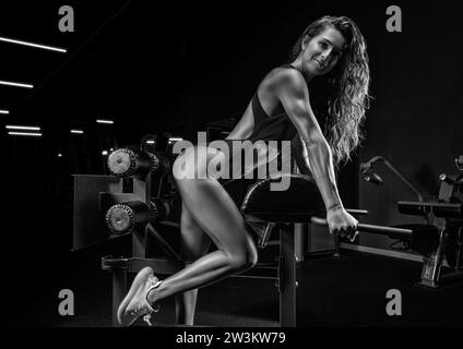 Incantevole bruna che fa iperestensione in palestra. Pompaggio posteriore. Vista laterale. Concetto di fitness e bodybuilding. Supporti misti Foto Stock