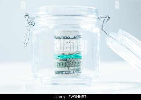 Una confezione di banconote da cento dollari si trova in un vaso di vetro. Il concetto di risparmio durante la crisi. Supporti misti Foto Stock