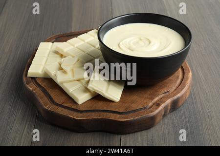 Gustosa pasta di cioccolato bianco in ciotola e pezzi su un tavolo di legno Foto Stock