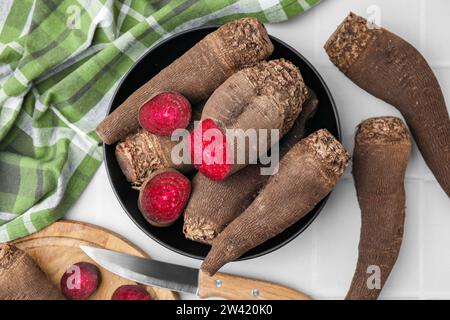 Recipiente con barbabietole rosse intere tagliate e coltello sul tavolo, piatto Foto Stock