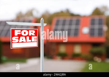 Cartello di vendita vicino a una bella casa all'aperto. Cartello rosso con le parole Foto Stock