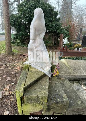 Statua coperta di plastica su una lapide nel cimitero pubblico Foto Stock