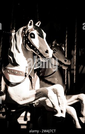 Cavalli vintage a giostra in un parco divertimenti buio catturati durante un nostalgico giro serale Foto Stock