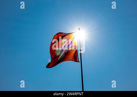 Splendida bandiera svizzera contro Blue Clear Sky e Sunbeam in una giornata ventosa in Svizzera Foto Stock