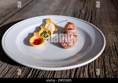 Un piatto con salsiccia Luganighe e con specie a cucchiaio come zafferano e parmigiano e rosmarino su un piatto su un tavolo di legno con luce solare Foto Stock