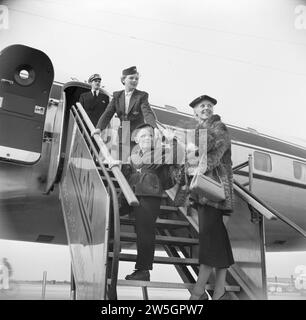 I passeggeri salgono a bordo di un aereo passeggeri KLM tramite le scale, dove vengono accolti da un portabandiera KLM e da una hostess CA. 1950 Foto Stock