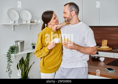 coppia felice senza bambini con caffè e succo d'arancia fresco che si guardano in cucina Foto Stock