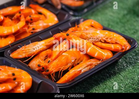 Deliziosi gamberi saltati con condimento cajun al banco in un contenitore di plastica. Foto Stock