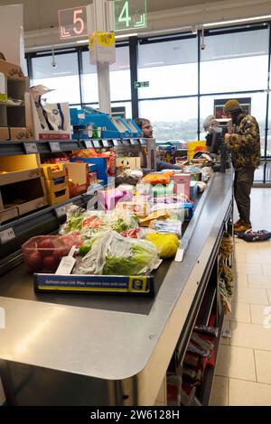 Cliente che paga alla cassa per cibo e dipendente che lavora al banco cassa del supermercato Lidl, Gran Bretagna, Regno Unito, KATHY DEWITT Foto Stock