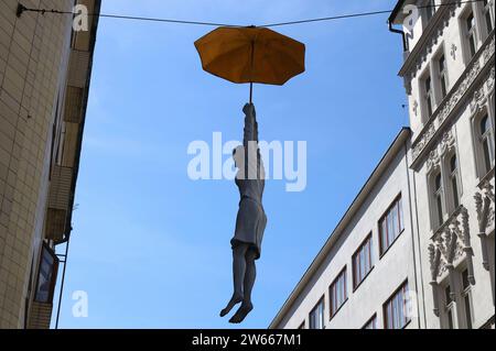 Scultura di una donna appesa a un ombrello sospeso sopra una strada di Praga Foto Stock