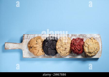 Una selezione di biscotti appena fatti in stile New York si è allineata su un tabellone e fotografata su uno sfondo semplice Foto Stock