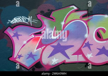 Street art urbana. Colorate lettere di graffiti e stelle, dipinte su un muro sotto il cavalcavia Fleetsbridge a Poole. Dorset, Inghilterra, Regno Unito, Regno Unito. Foto Stock