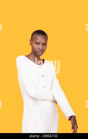 Ritratto di una giovane donna afro-americana sicura e calma con i capelli corti in bianco mentre guardi la macchina fotografica su sfondo giallo Foto Stock
