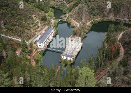 Vista aerea del ponte tra edifici e centrali elettriche sul fiume, circondato dal paesaggio della Galizia Foto Stock