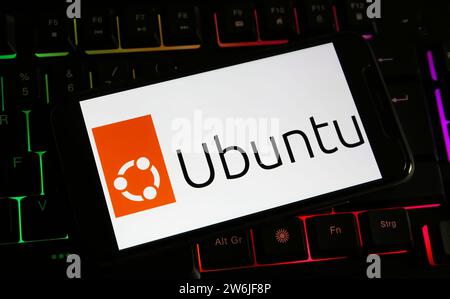 Viersen, Germania - 9 dicembre. 2023: Primo piano dello smartphone sulla tastiera del computer con il logo di Ubuntu Foto Stock
