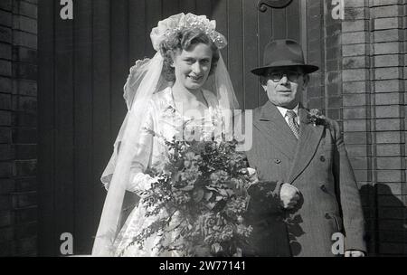 Anni '1950, storico, matrimonio, una sposa in piedi con suo padre, indossando un abito e un cappello a doppio petto, per una foto all'esterno dell'ingresso della chiesa, Inghilterra, Regno Unito. Foto Stock
