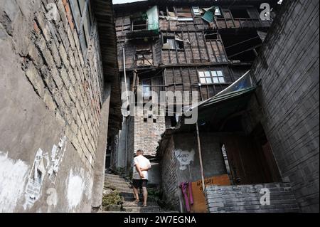 04.08.2012, Cina, Chongqing, - Un uomo che sale una vecchia scalinata in pietra nell'area delle diciotto scale, superando le case tradizionali nella città vecchia dello Shi Foto Stock