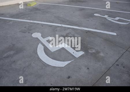 La sedia a rotelle verniciata a terra segnala l'esistenza di uno spazio di parcheggio riservato ai conducenti disabili Foto Stock