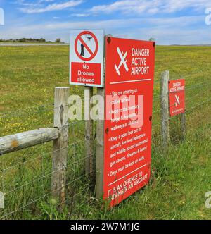 Un segnale di avvertimento con la scritta "Danger - Active Airport" (pericolo - aeroporto attivo) presso Land's End Airport, St. Solo, Cornovaglia, Inghilterra, Regno Unito Foto Stock