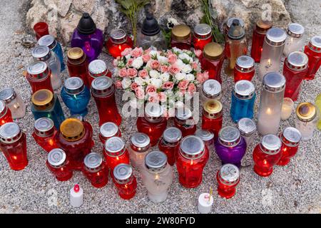 Molte candele funerarie (candele commemorative) in portatori di vari colori (blu, rosso, contenitori trasparenti) su un cimitero; con fiori; viste dall'alto Foto Stock