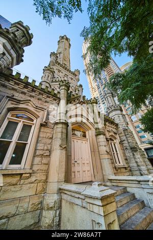 Ingresso e torre della torre d'acqua di Chicago con un lussureggiante albero verde, turismo della città, attrazione storica Foto Stock