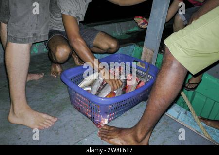 Maldive - 5 ottobre 2013: Un gruppo di pescatori in un'amichevole pesca notturna con un cestino pieno di pesce. Foto Stock