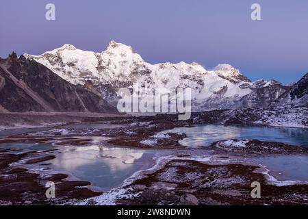 Terra ghiacciata delle Highland. Campo base del monte Cho Oyu (8188 m) in Himalaya, Nepal. Laghi d'alta quota e creste di montagna con la luce del tramonto. Foto Stock