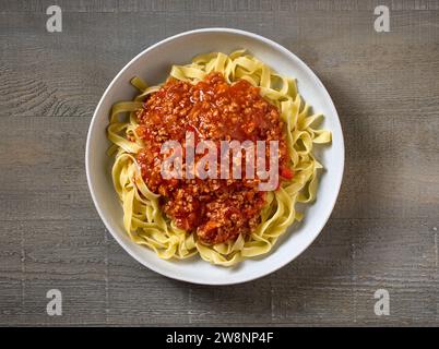 ciotola di tagliatelle di pasta con salsa bolognese su un tavolo da cucina in legno, vista dall'alto Foto Stock