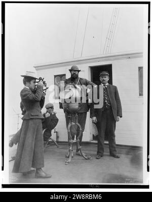 Donna che guarda attraverso il sestante a bordo della nave della spedizione, George W. Elder, con due uomini e il capitano Peter Doran durante la spedizione Harriman in Alaska, 1899) - Curtis Foto Stock