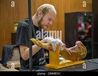 Kiev, Ucraina - 30 settembre 2023: Chef uomo affettare con cura il jamon della gamba di maiale durante il Be Wine International Wine Show. Foto Stock