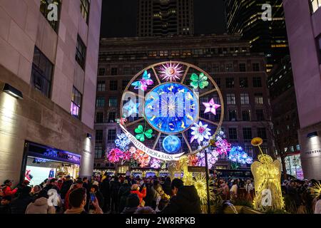 New York, USA, 20 dicembre 2023. La gente guarda uno spettacolo di luci e suoni spettacolari durante le vacanze sulla Saks Fifth Avenue a New York City, il Rockefeller Center A. Foto Stock